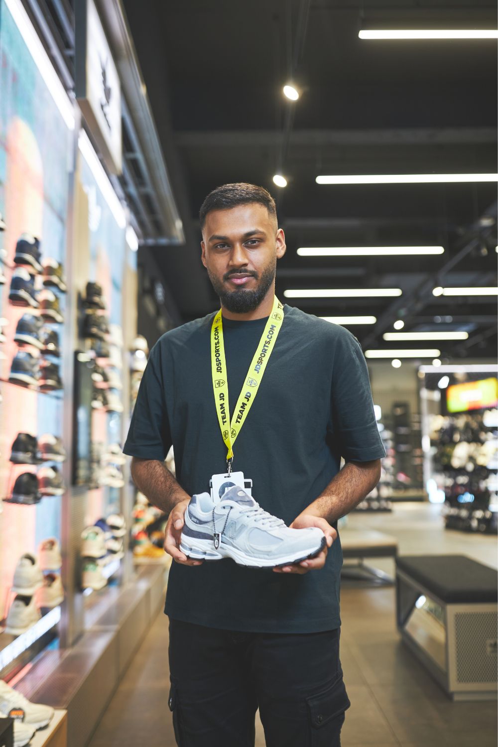 A man stands in a store, holding a stylish pair of sneakers, ready to show them off.