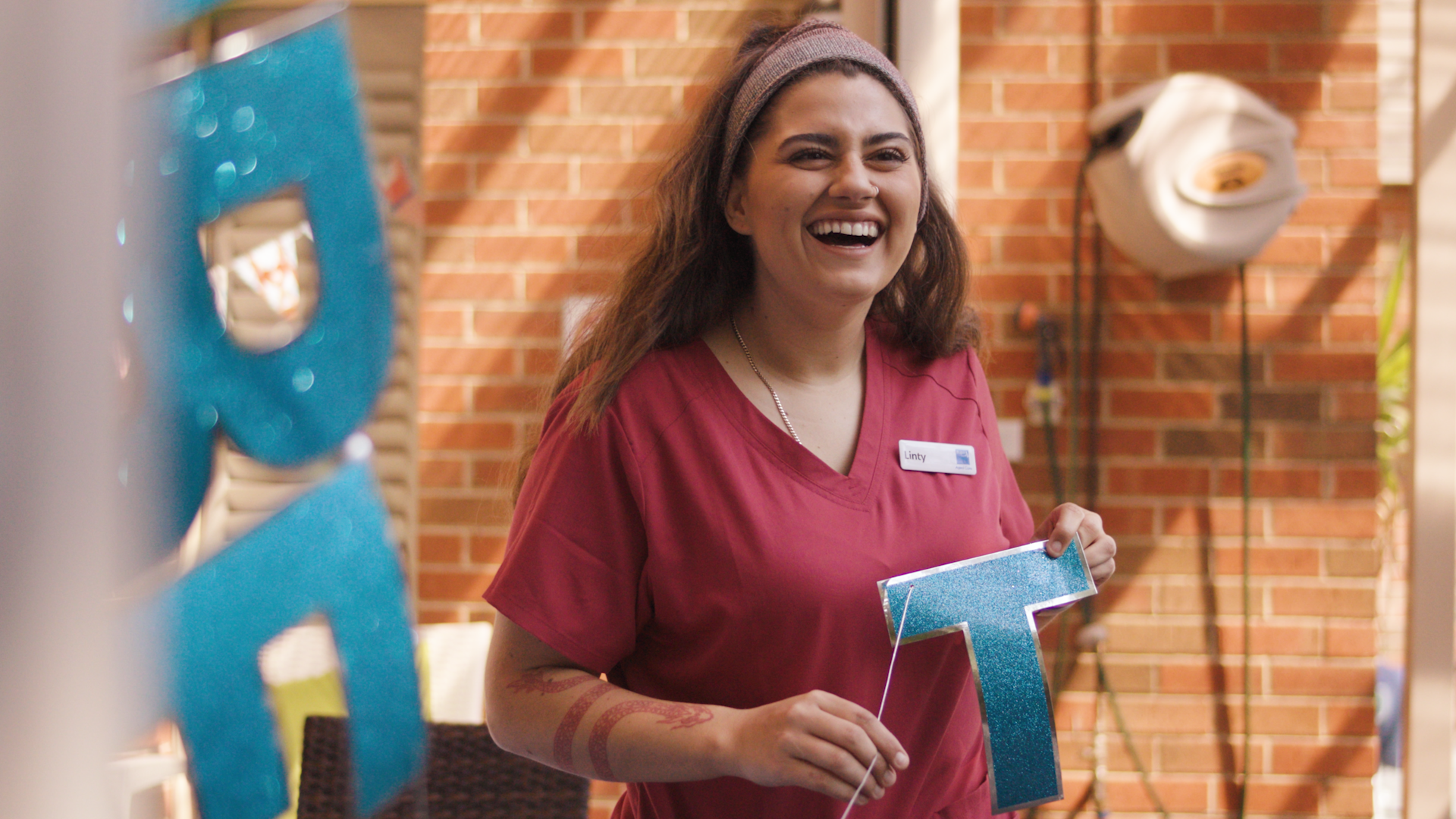 Bupa Carer in burgundy uniform holing up a celebration banner