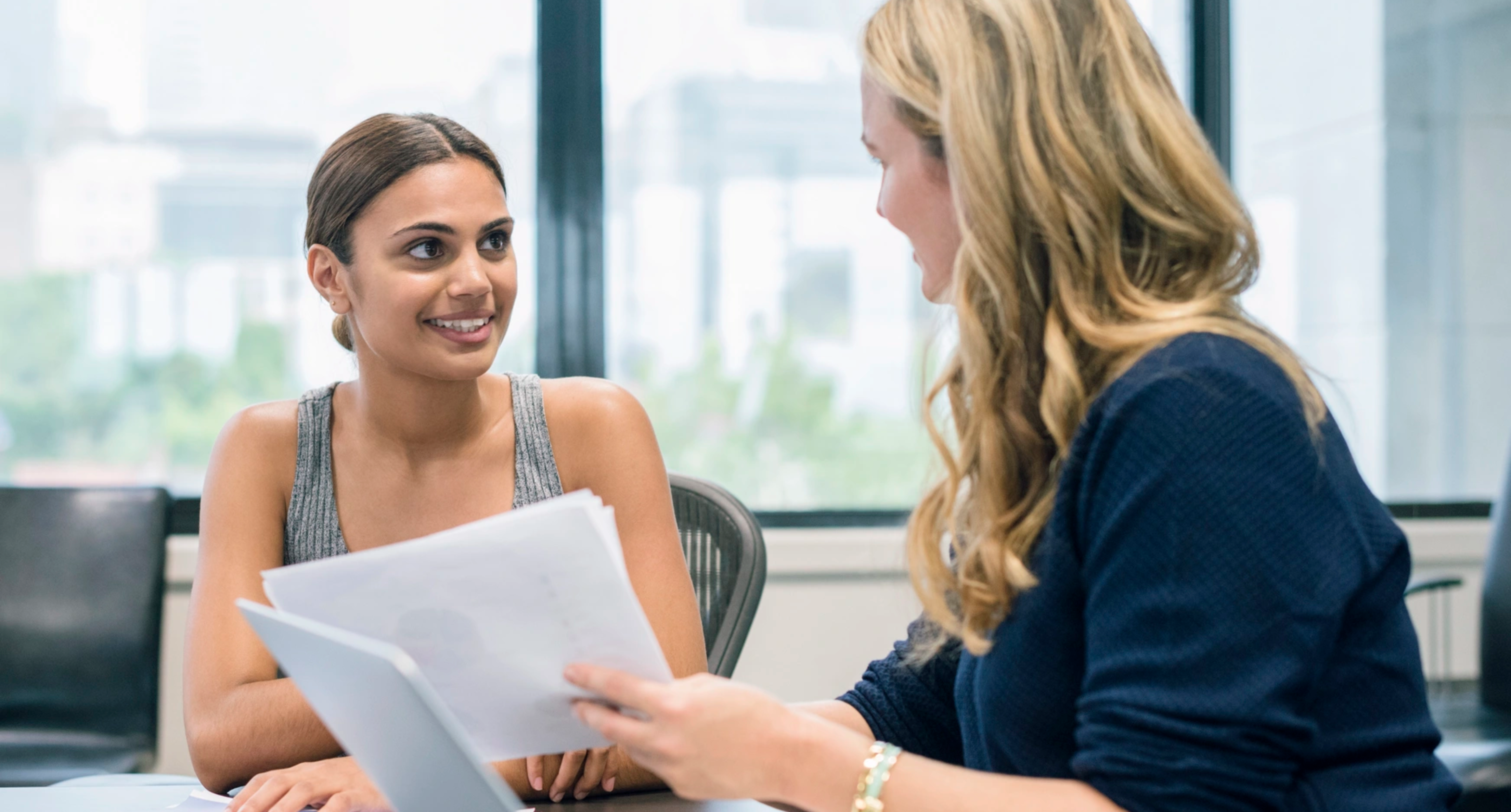 Manager holding paper talking to young professional in office