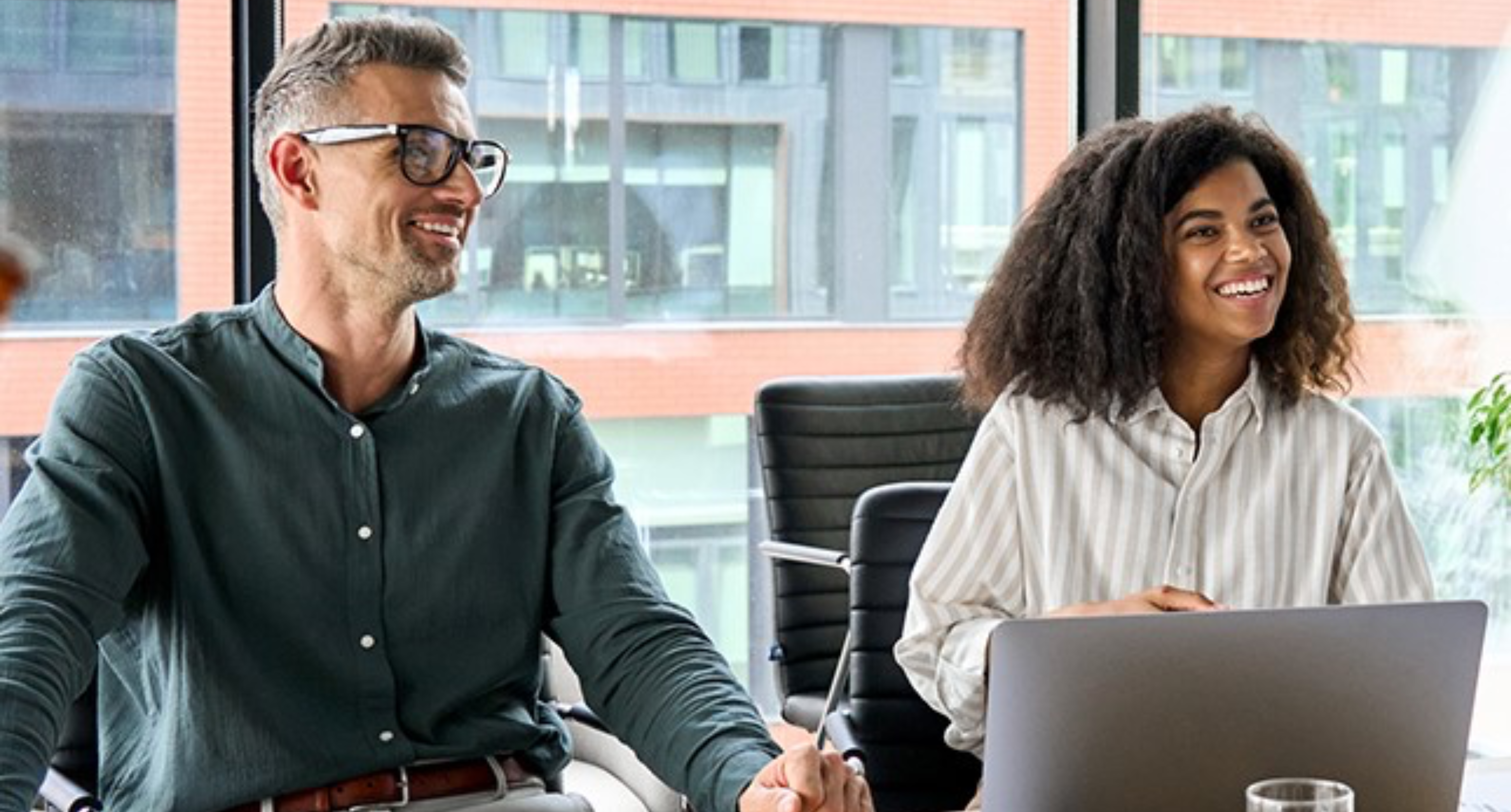 Two professionals laughing sat in a meeting room