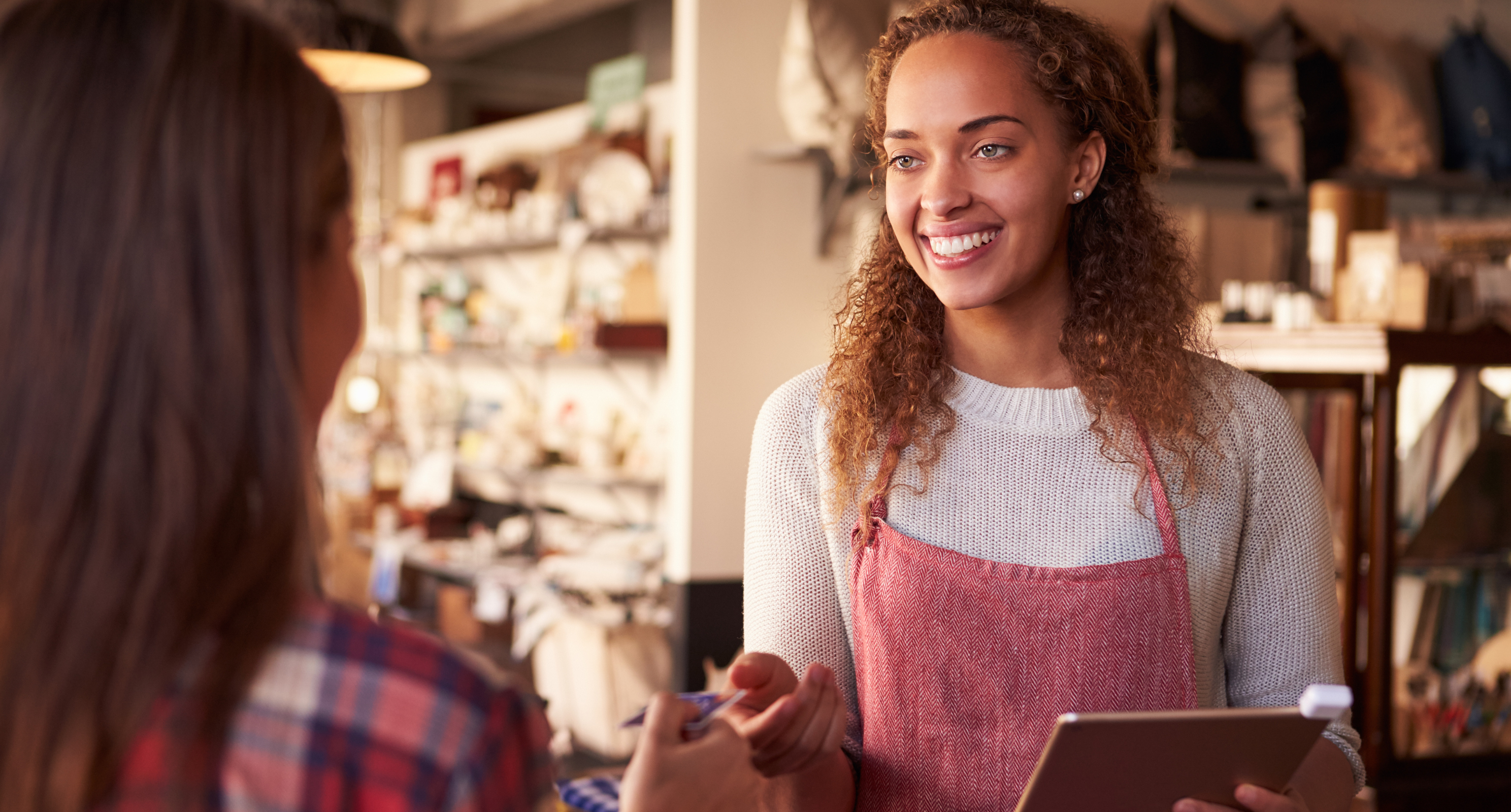 Young woman working at a store till handing a customer a bank card