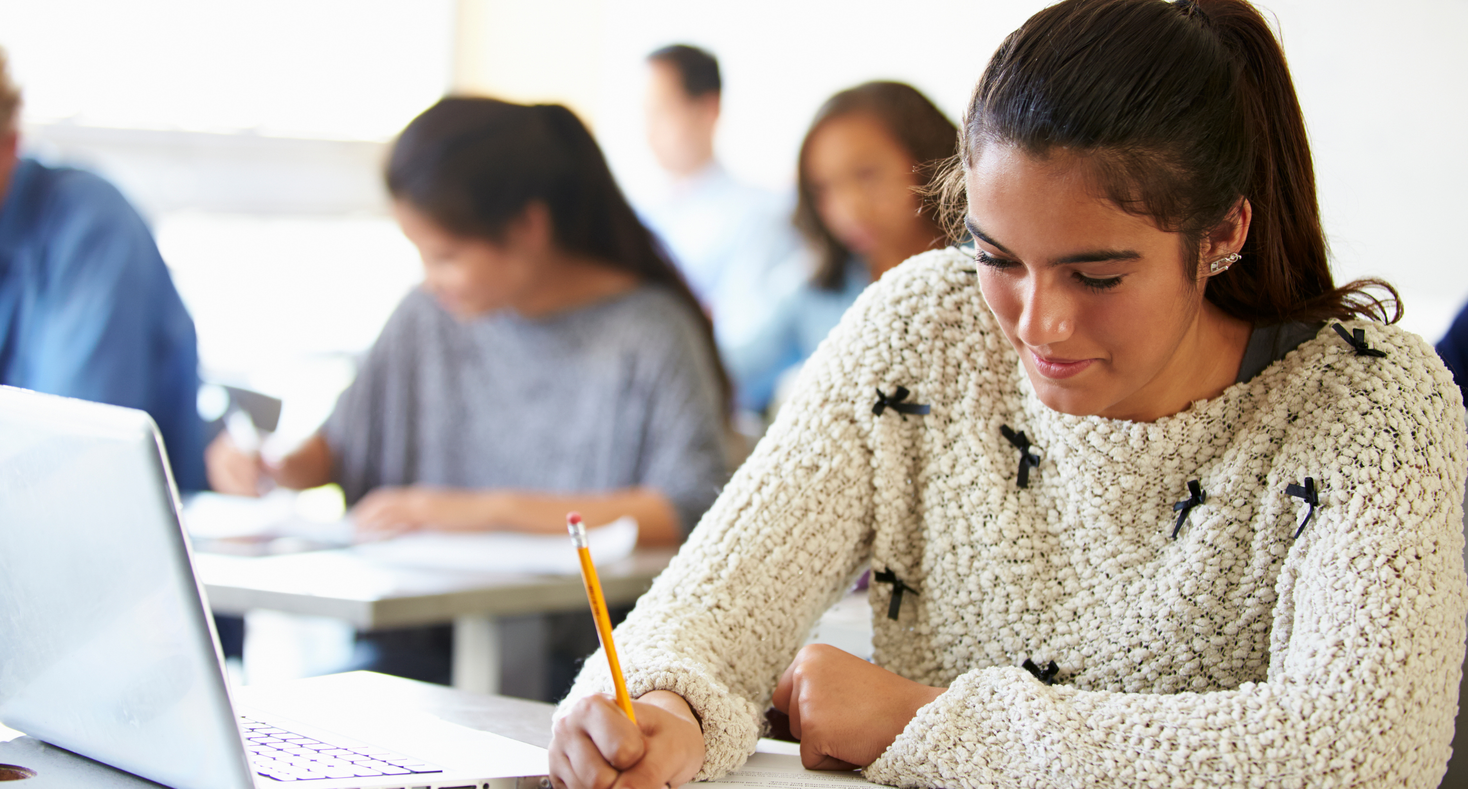 Student sat at desk writing on paper