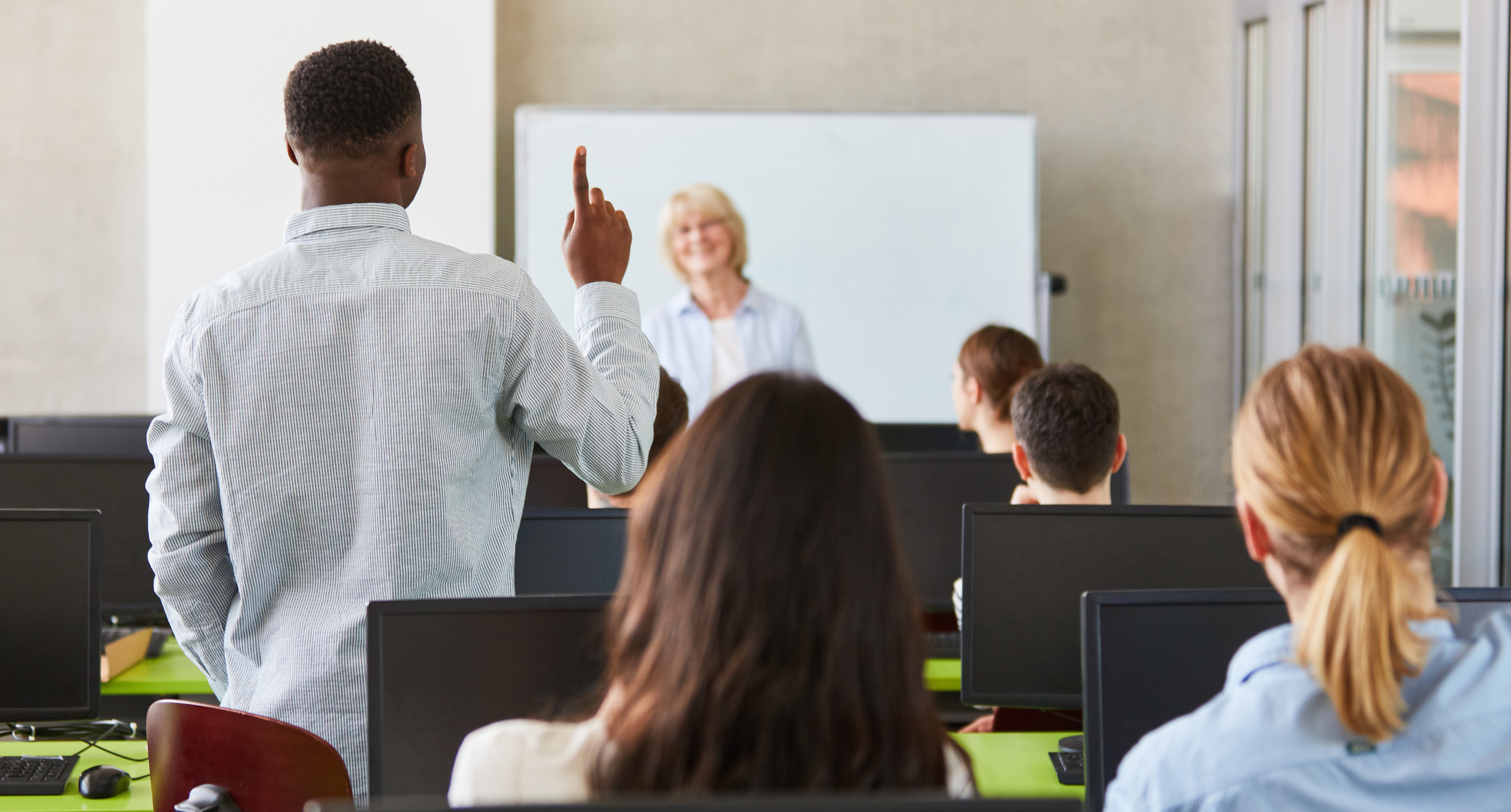 Teacher in classroom taking a question from a student