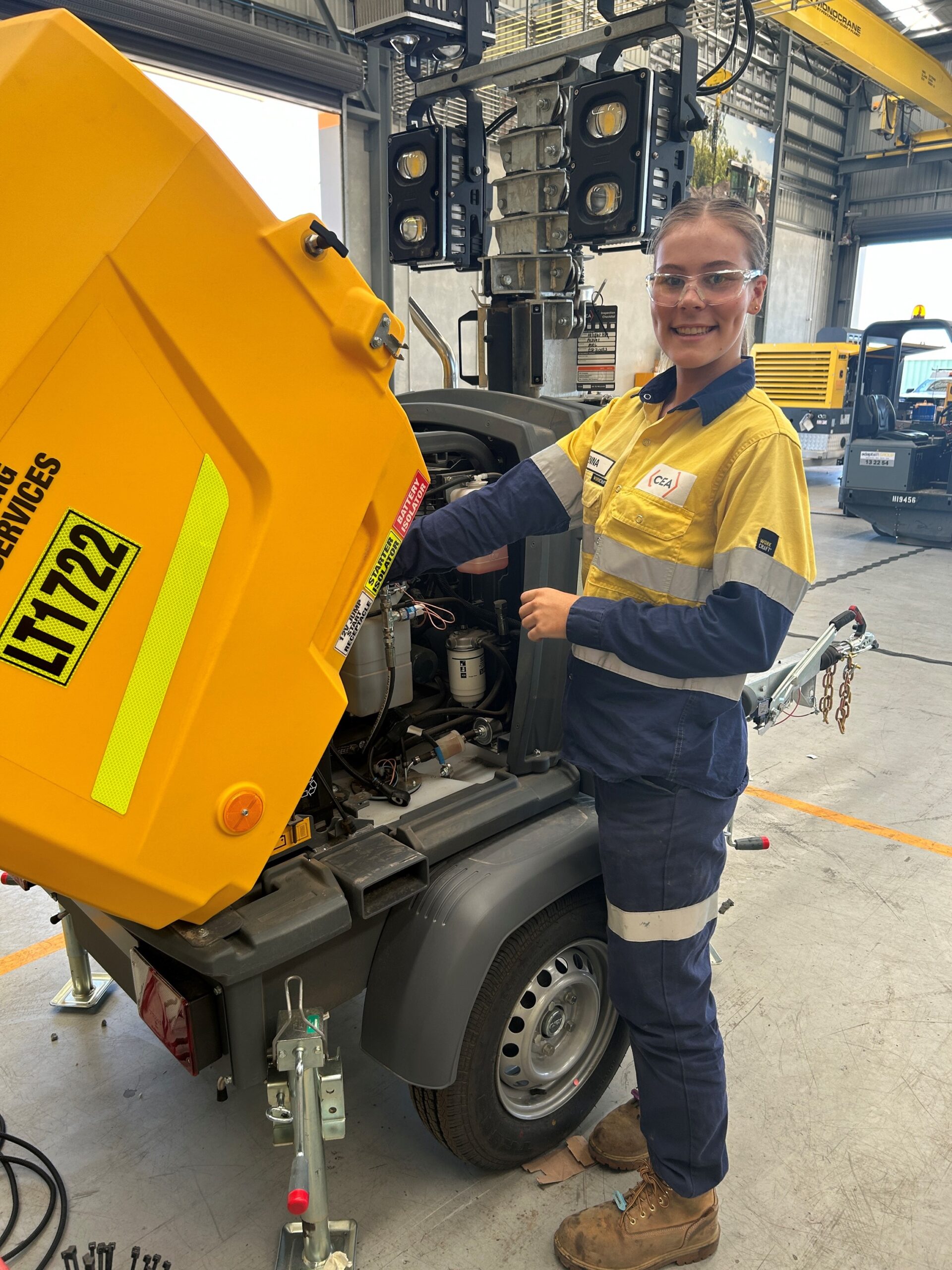 Apprentice Sienna working on heavy equipment wearing high vis