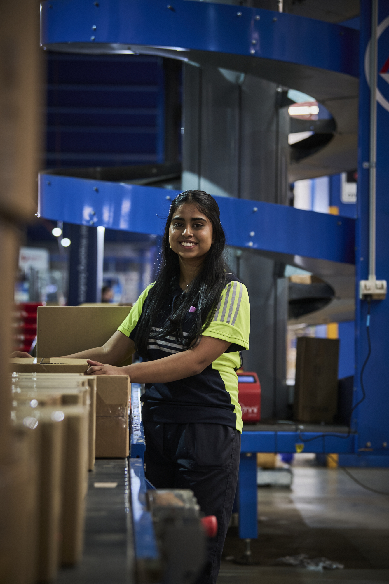 young female mainfreight worker stood next to boxes in warehouse